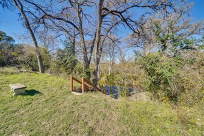 A grassy area with a stone bench and a wooden structure. - Bandera Carriage House w/ Medina River Access! (Bandera)
