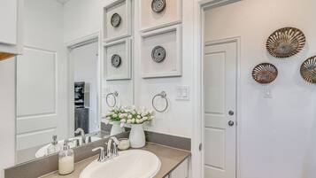 A bathroom with a white sink, mirror, and decorative plates on the wall.