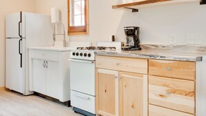 Eine Küche mit weißen Geräten, Holzschränken und einer Kaffeemaschine auf der Arbeitsplatte.