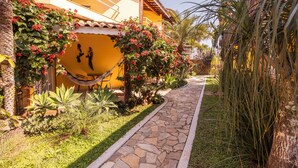 A pathway leading to a building with a yellow facade and a stone-tiled entrance. - Pousada Bonns Ventos (Ilhabela)