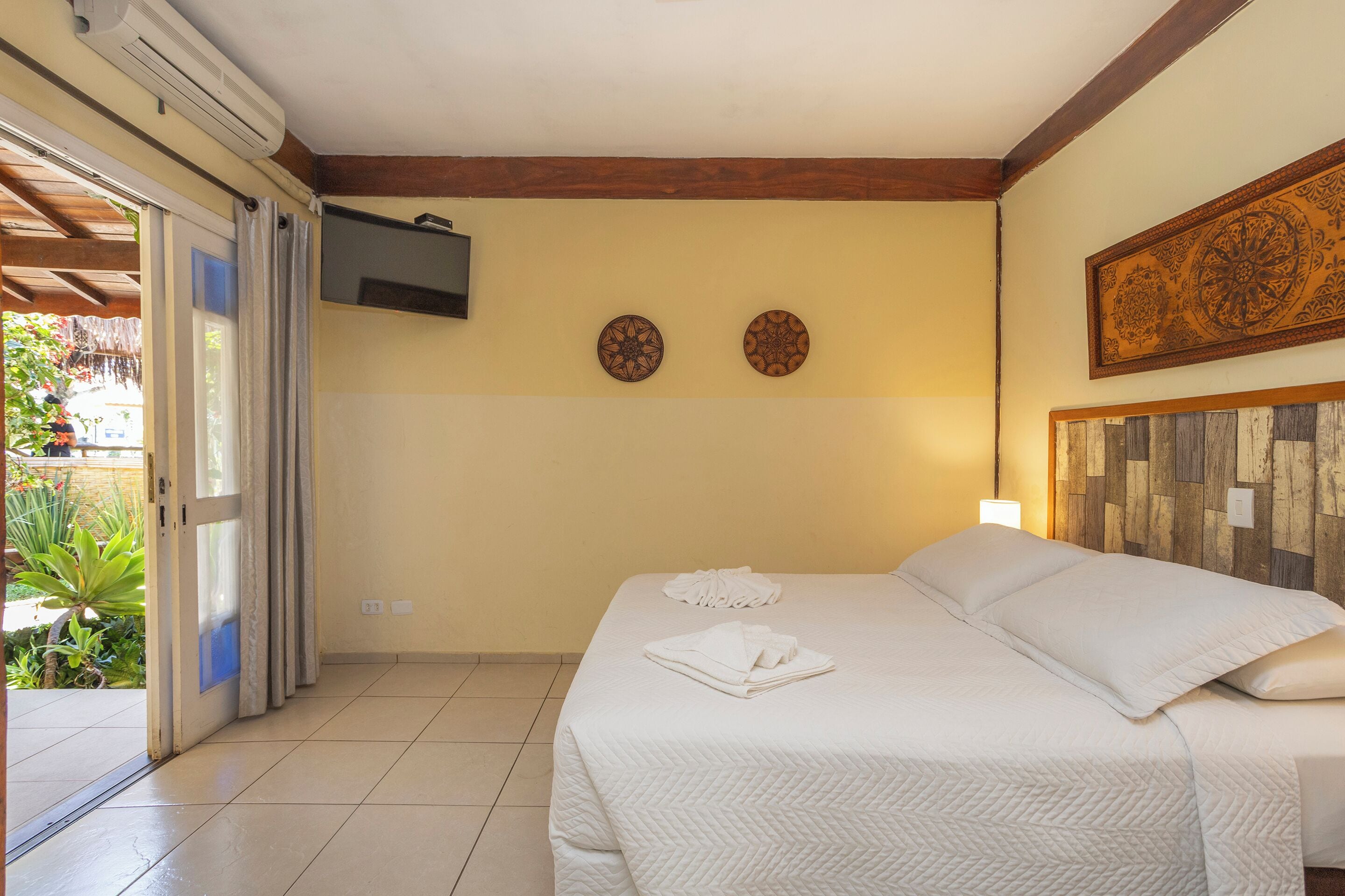 A hotel room with a bed, a TV mounted on the wall, and two decorative plates.