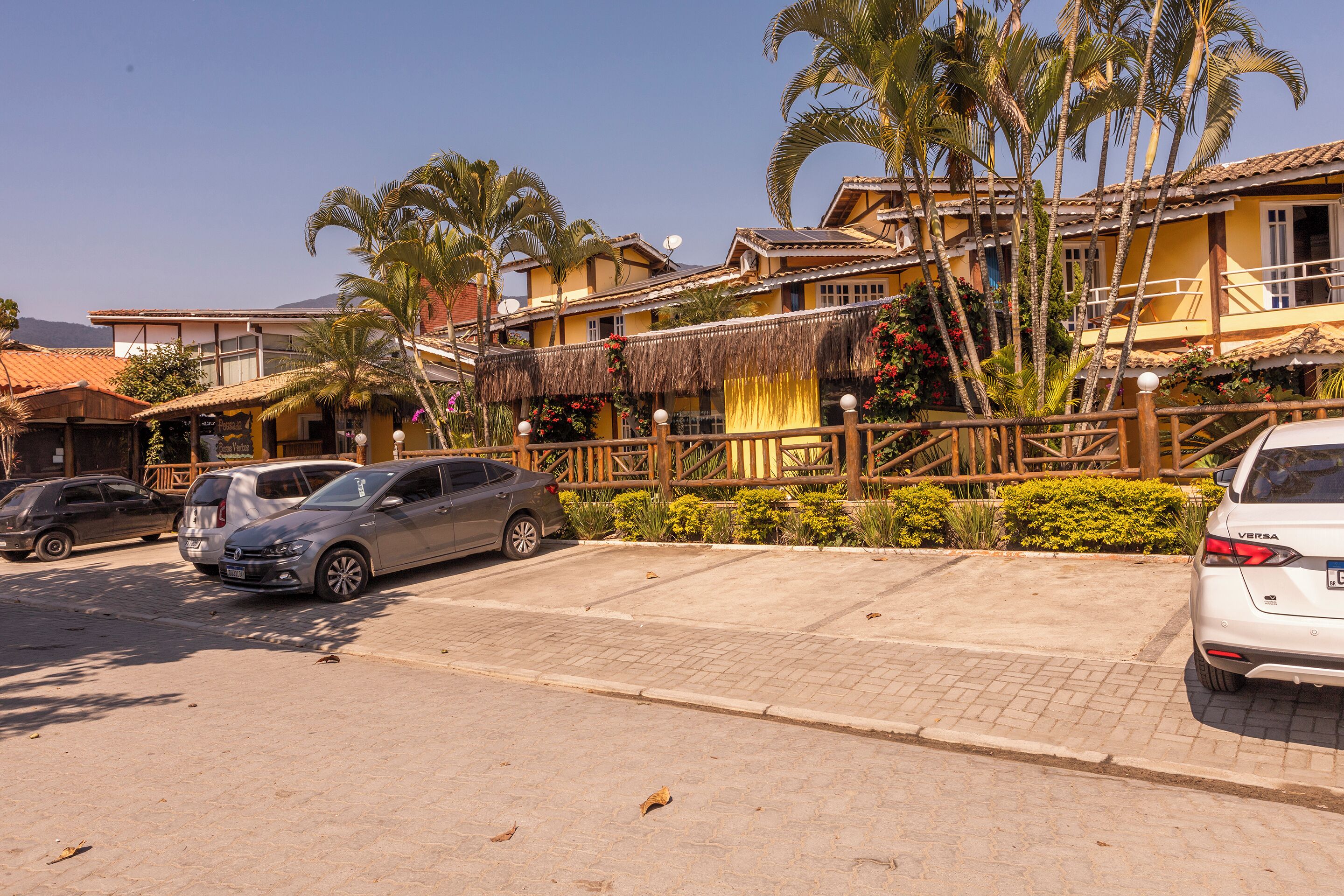 A hotel with multiple-story buildings, a paved parking area, and palm trees.