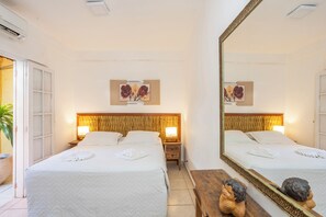 Ein Hotelzimmer mit zwei Betten, einem großen Spiegel und einem hölzernen Kopfteil.
