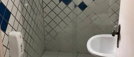 Un baño pequeño y con azulejos, con inodoro, lavamanos y zona de ducha.