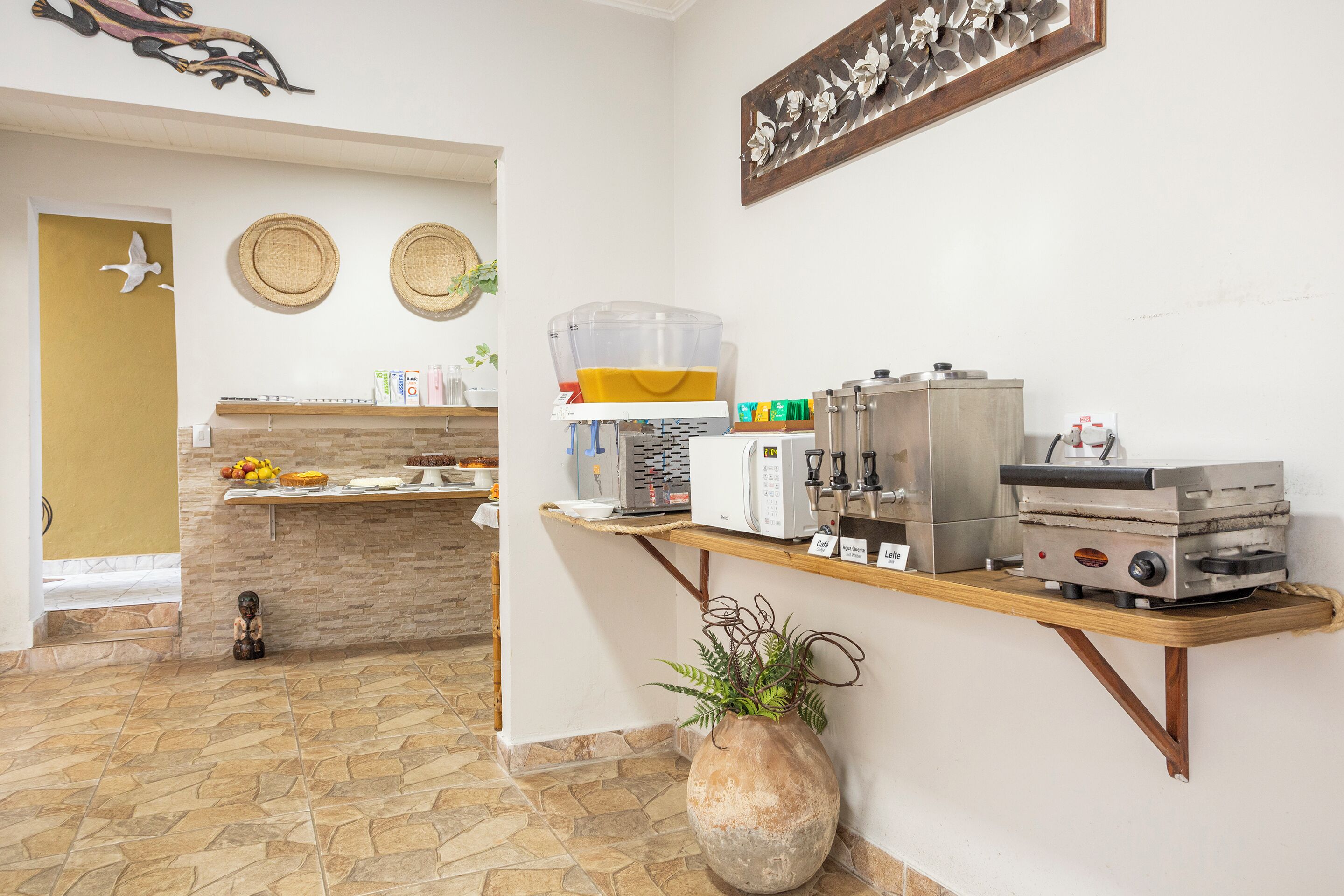 A kitchen area with a coffee machine, a large water dispenser, and a food display.