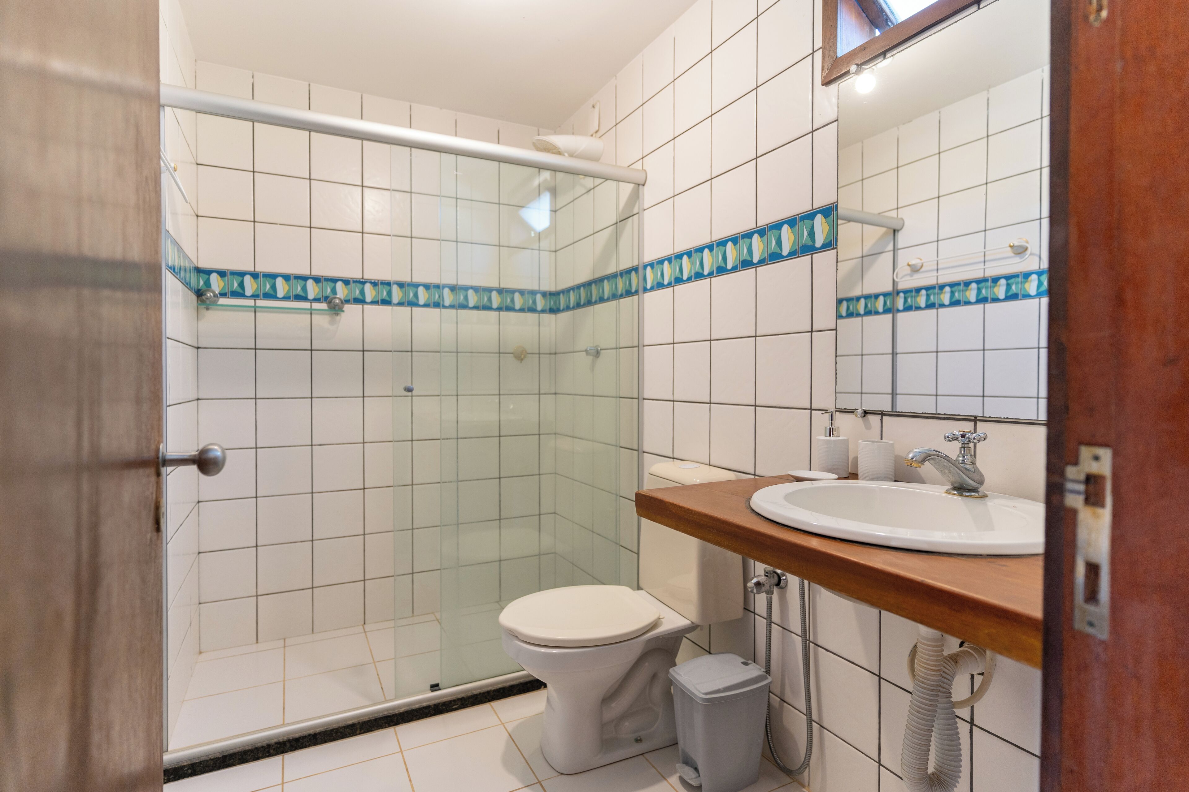 A bathroom with a shower, toilet, sink, and a mirror.