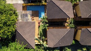 Un resort moderno con varias edificaciones de techo triangular, una piscina central y abundante vegetación.