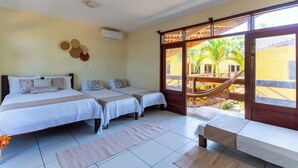 Habitación de hotel con dos camas, un ventanal con vistas al exterior y una hamaca fuera de la ventana.