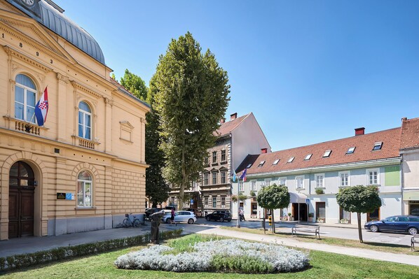 A historic building with a dome, a flag, and a well-maintained garden. - Aminess Kadoor Hotel (Karlovac)