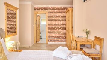Een slaapkamer met een bed, een houten bureau, een stoel, een raam met uitzicht en een bakstenen muur.