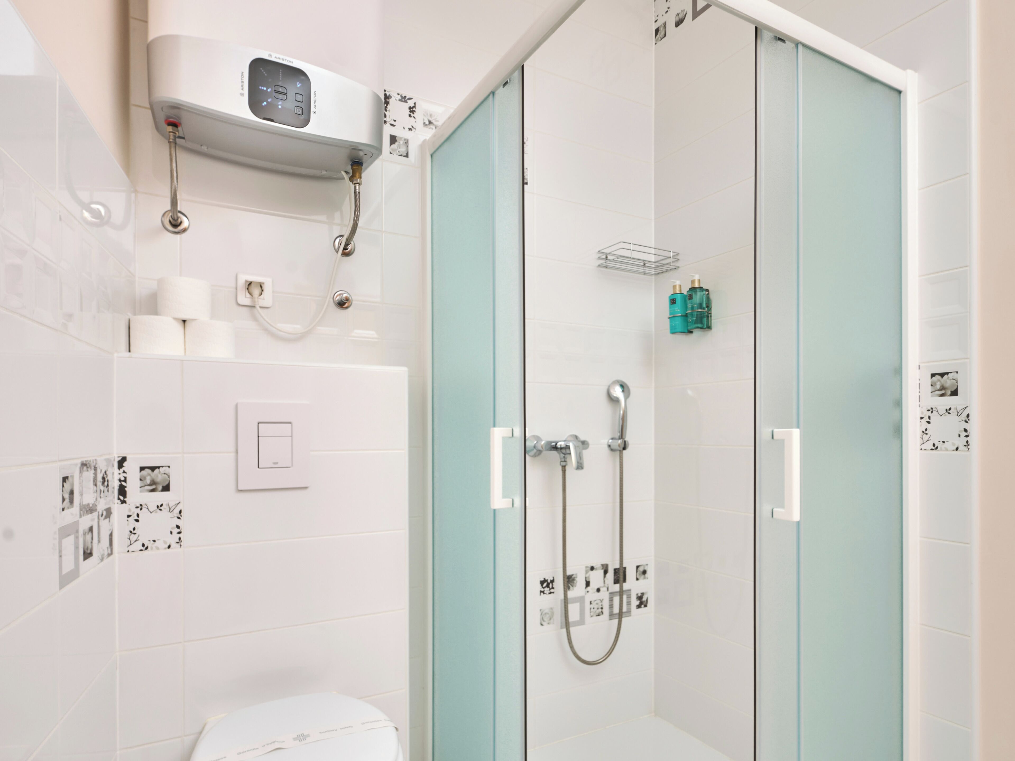 A modern bathroom with a glass shower enclosure, a toilet, and a wall-mounted heater.