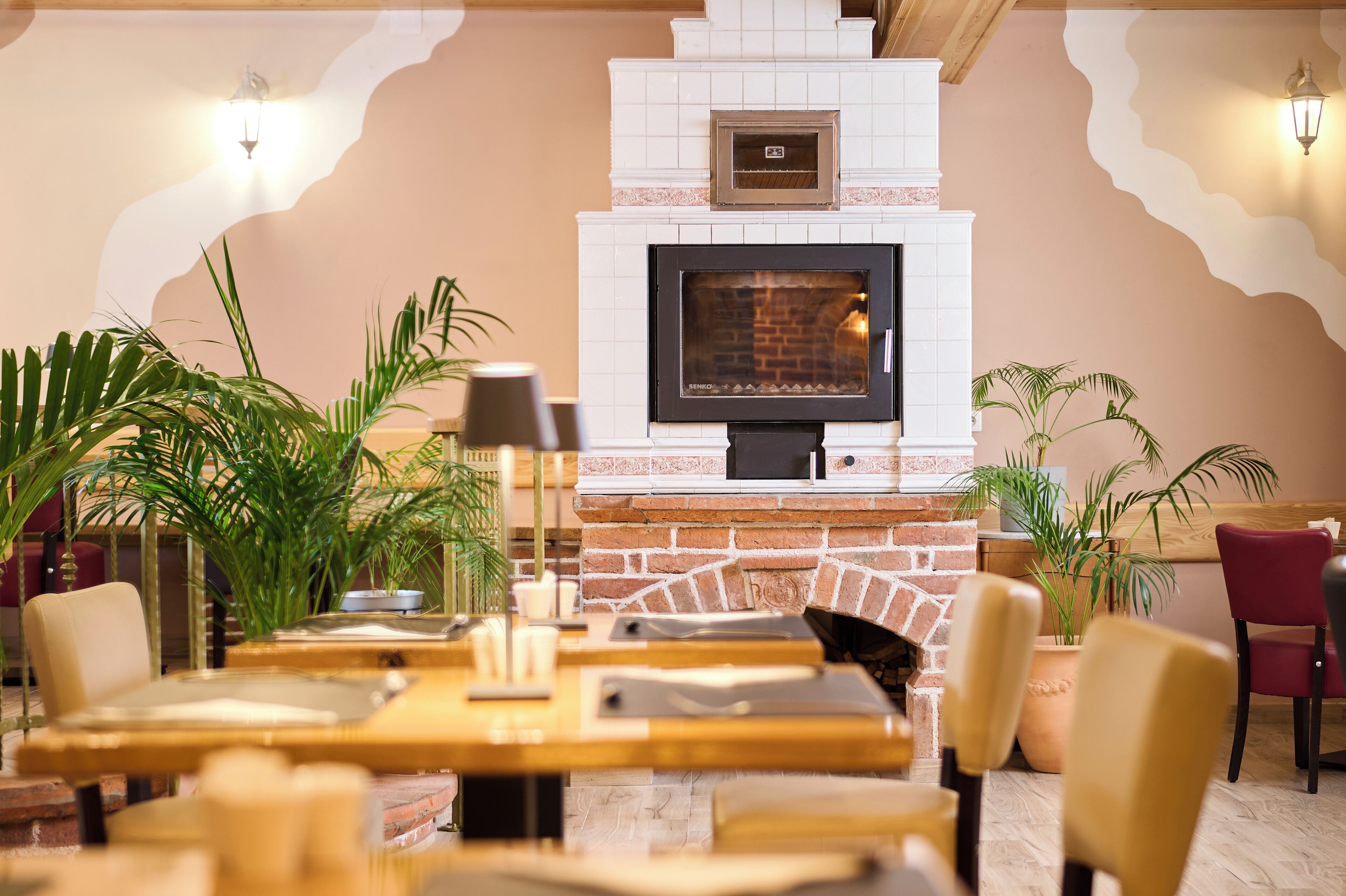 Un restaurant doté d’une cheminée en briques, de tables en bois et de plantes en pot.