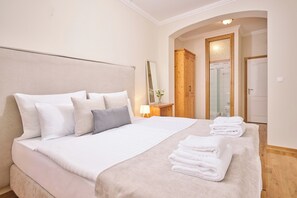 A hotel room with a large bed, a wooden wardrobe, a mirror, and a bathroom visible through an archway. - Aminess Kadoor Hotel (Karlovac)
