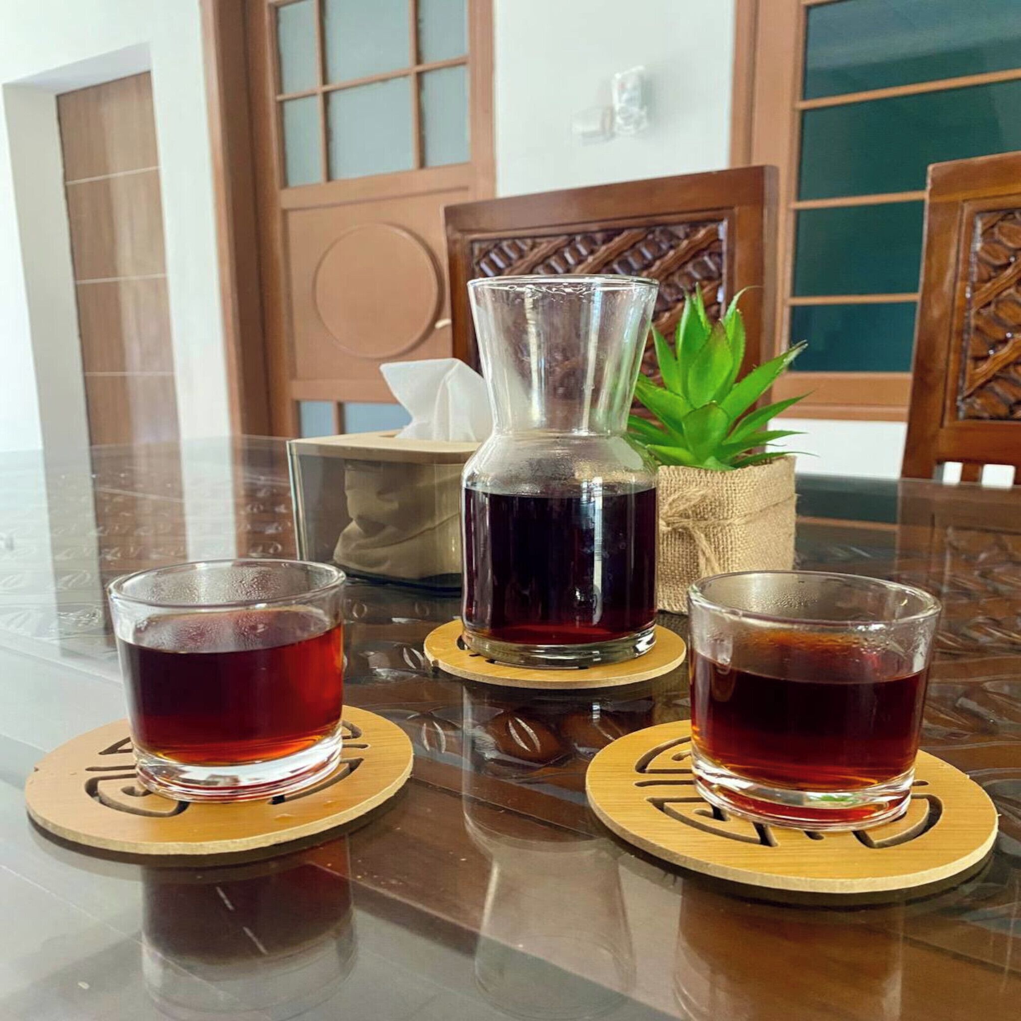 Une table avec deux verres de thé et une théière, le tout posé sur des sous-verres.