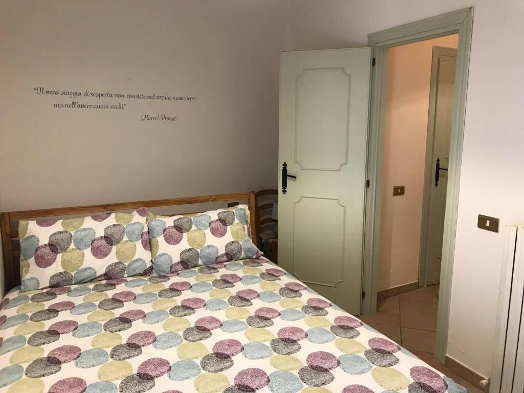 A bedroom with a bed, a door, and a wall with a quote.
