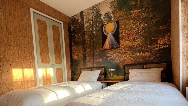 A bedroom with two beds, a wooden floor, a large window, and a wall mural. - Logement Entier : Hébergement - Sevran, France (Sevran)