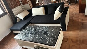 A modern living room with a black sectional sofa, a white coffee table with a floral design, and a patterned rug. - Logement Entier : Hébergement - Sevran, France (Sevran)