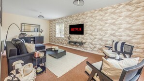 A modern living room with a textured wall, a black sofa, a coffee table, and a TV mounted on the wall.
