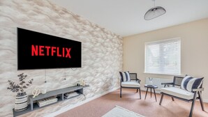 A living room with a large flat-screen TV mounted on a textured wall, a sofa, a coffee table, and a small side table.