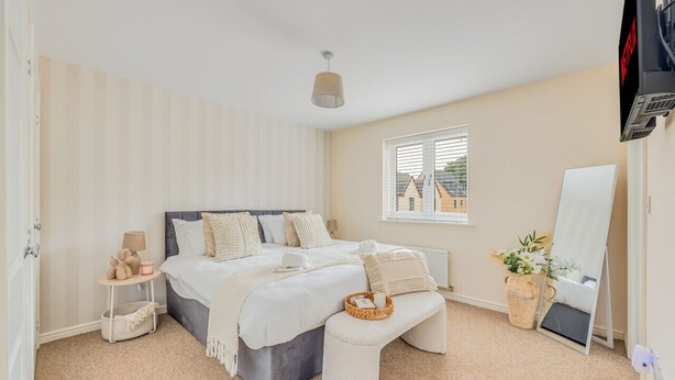 A bedroom with a bed, bedside table, lamp, and a window with blinds.