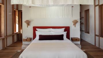 Una cama bien hecha con ropa de cama blanca y roja, cabecero de madera y mesitas de noche con lámparas.
