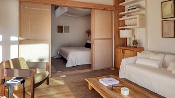 Una habitación con una cama, un sofá, una mesa de centro de madera, una silla y una estantería.