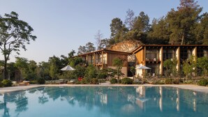A pool with a wooden deck, a building with large windows, and surrounding trees. - Ahama - Relais & Châteaux (Fethiye)