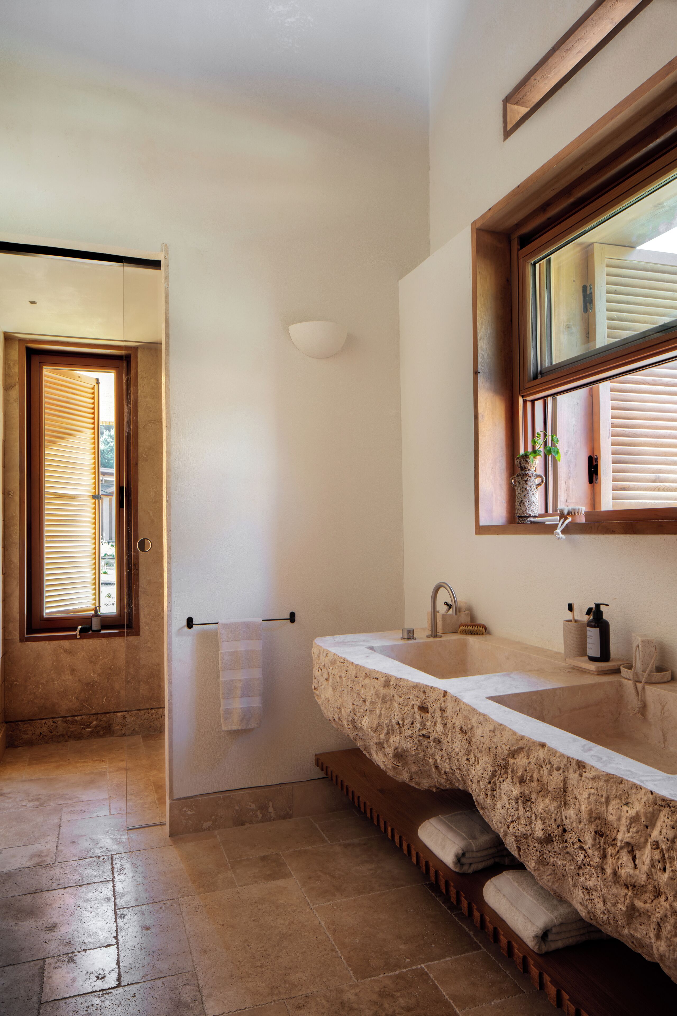 A bathroom with a large stone sink, a wooden door, and a towel rack.