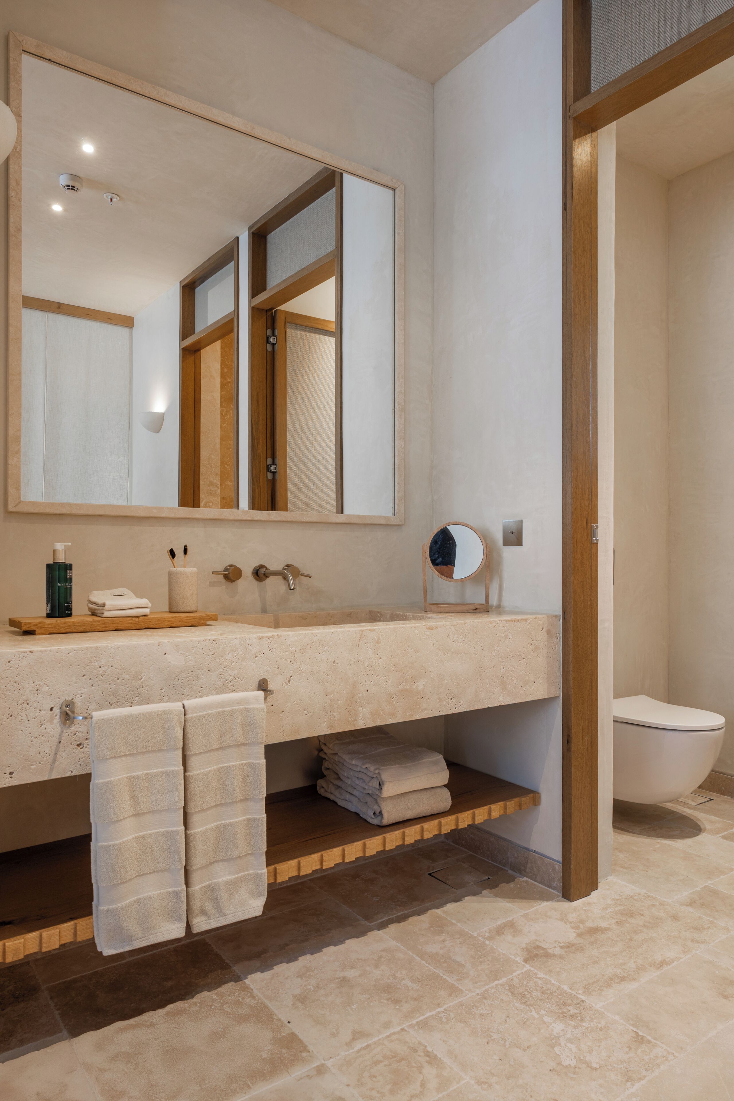 A bathroom with a large mirror, a sink, a toilet, and a towel rack.
