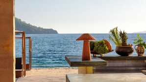 An outdoor seating area with a view of the sea, featuring a wooden table, a wicker lamp, and potted plants. - Ahama - Relais & Châteaux (Fethiye)