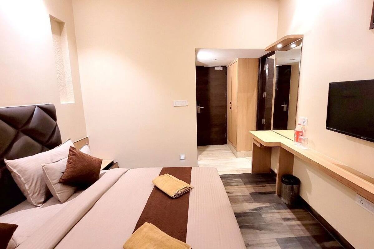 Ein Hotelzimmer mit Bett, Schreibtisch, Fernseher und Spiegel.