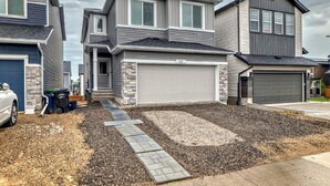 A modern two-story house with a garage, driveway, and a stone accent wall.