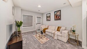 A living room with a sofa, a coffee table, a TV, and a plant.