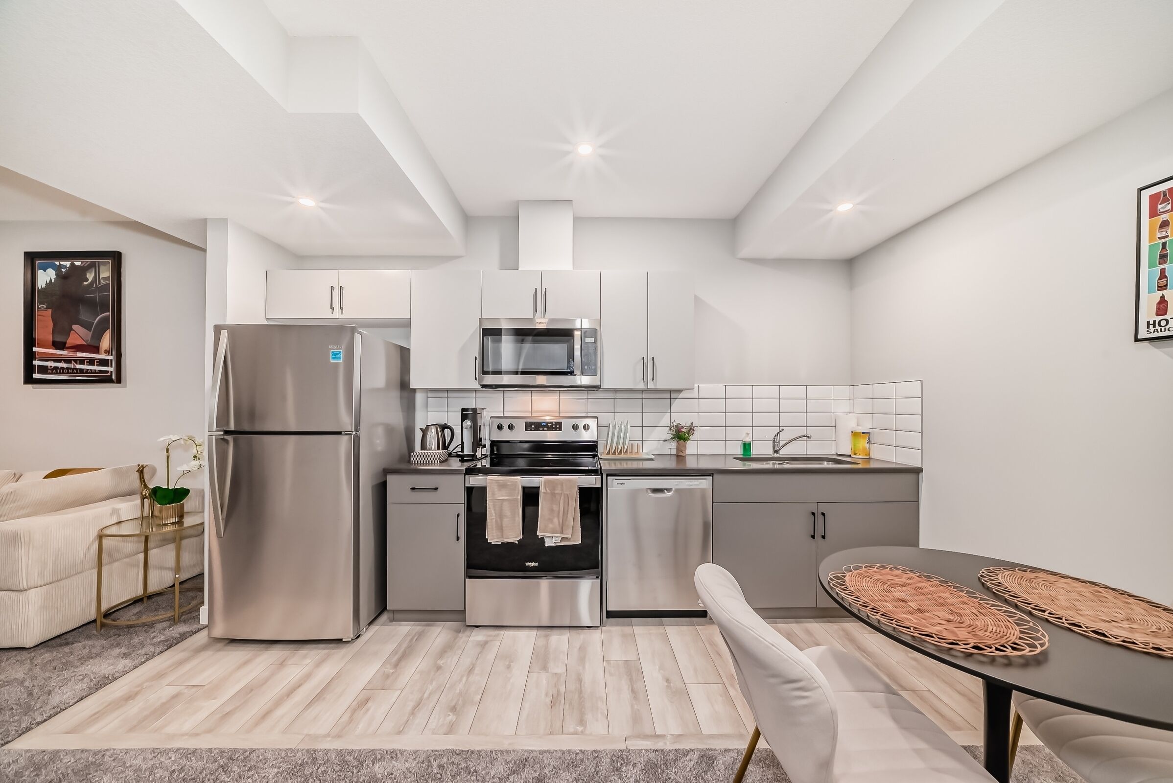 A modern kitchen with stainless steel appliances, a dining area with a round table, and a sofa.