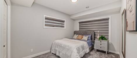 A bedroom with a bed, nightstand, and a window with blinds.