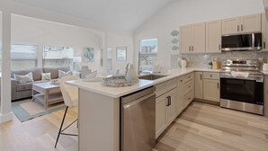 A modern kitchen with a central island, stainless steel appliances, and light-colored cabinetry. - Coconut Sunsets A & B on Estero Blvd, 7 Bedroom Hom by RedAwning (Fort Myers Beach)