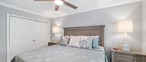 A bedroom with a bed, two nightstands, a ceiling fan, and a door.