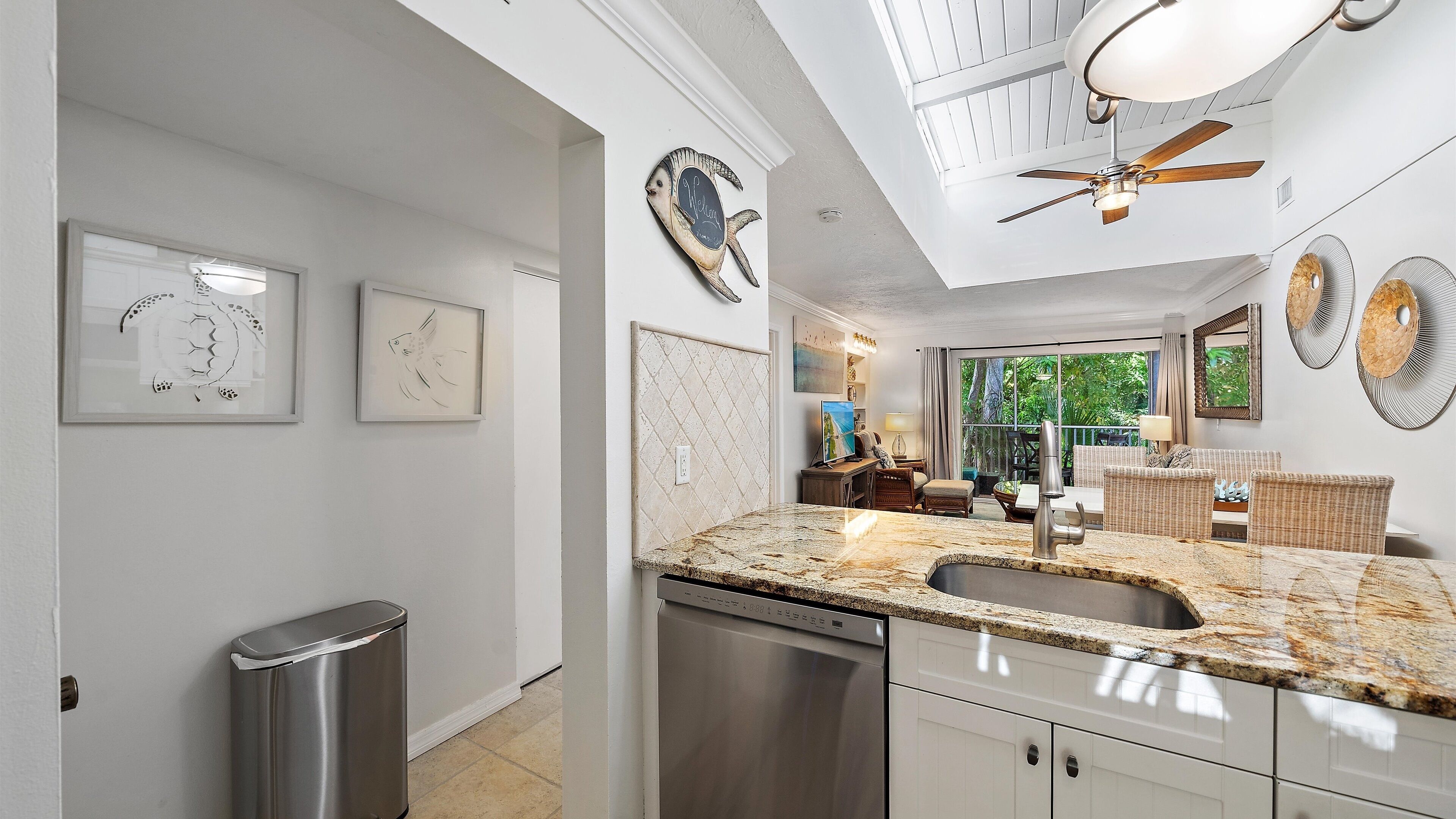 A modern kitchen with granite countertops, a built-in dishwasher, and a ceiling fan.