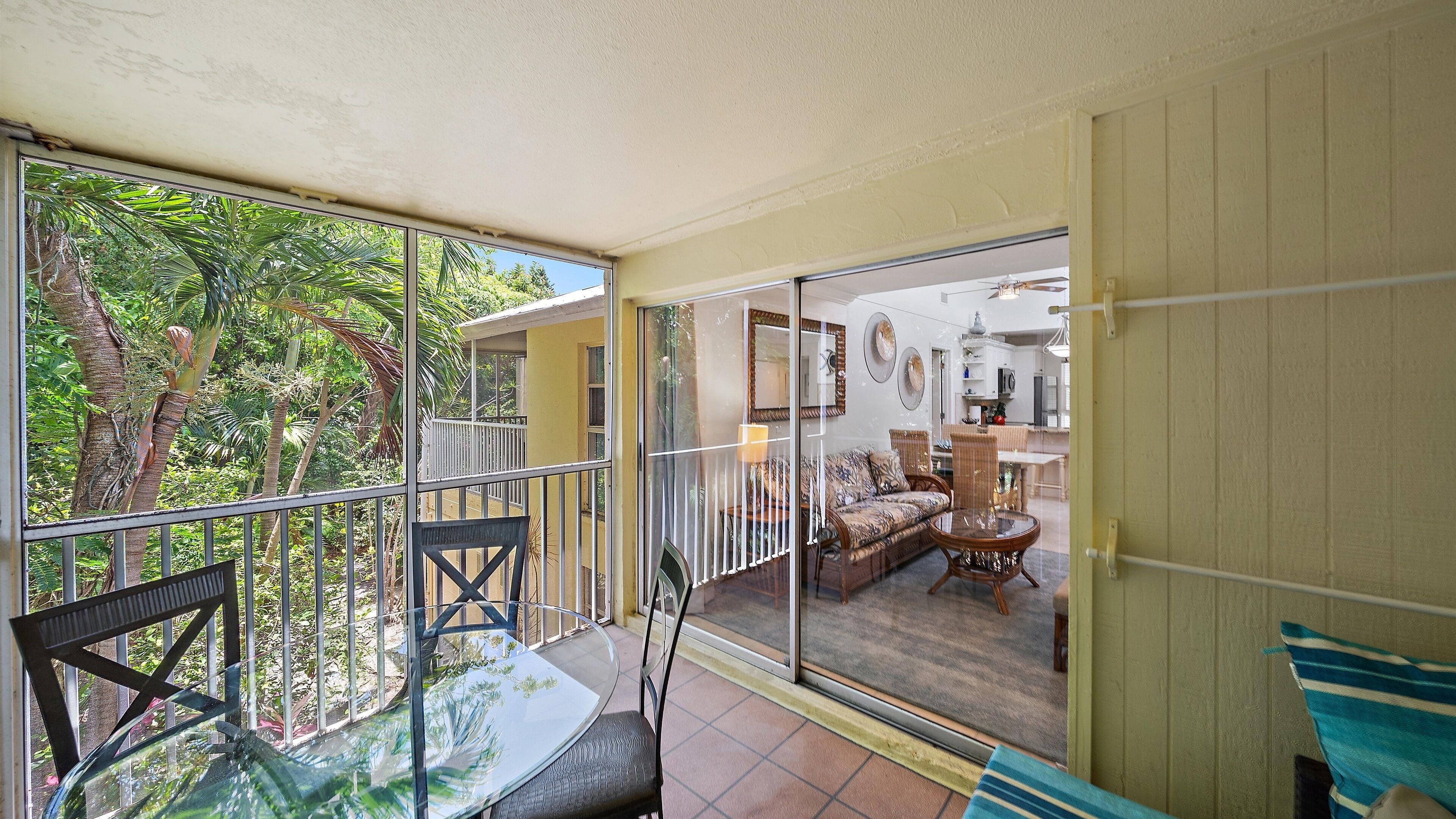 Un balcon avec une porte vitrée donnant sur un espace de vie comprenant un canapé, des fauteuils et une table à manger.