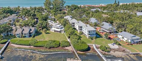 An aerial view of a coastal residential area with houses, a pier, and a beach.