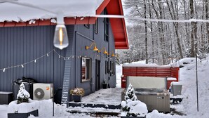 Une maison avec un toit rouge, un garage et une véranda couverte.