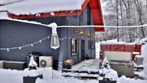 Une maison avec un toit rouge et une façade grise, entourée de neige.