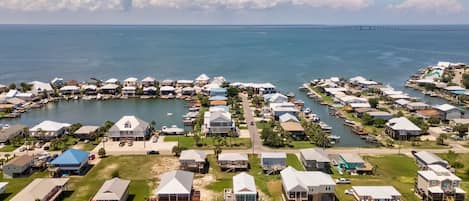 Zona residencial costera con casas, un puerto deportivo y un puente al fondo.