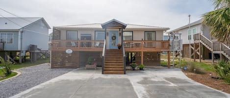 A two-story building with a front porch, a staircase, and a deck.