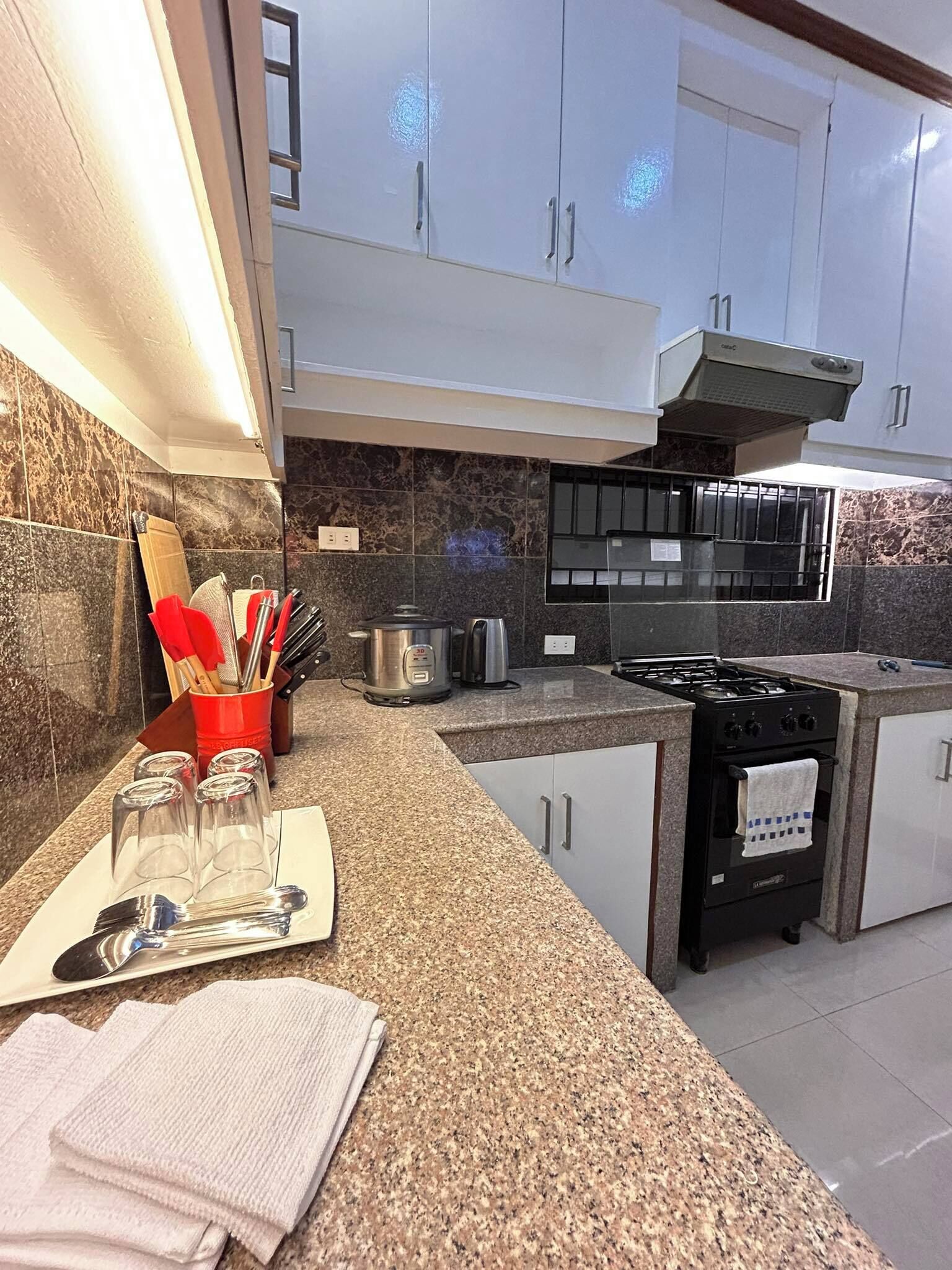 A modern kitchen with granite countertops, stainless steel appliances, and white cabinetry.