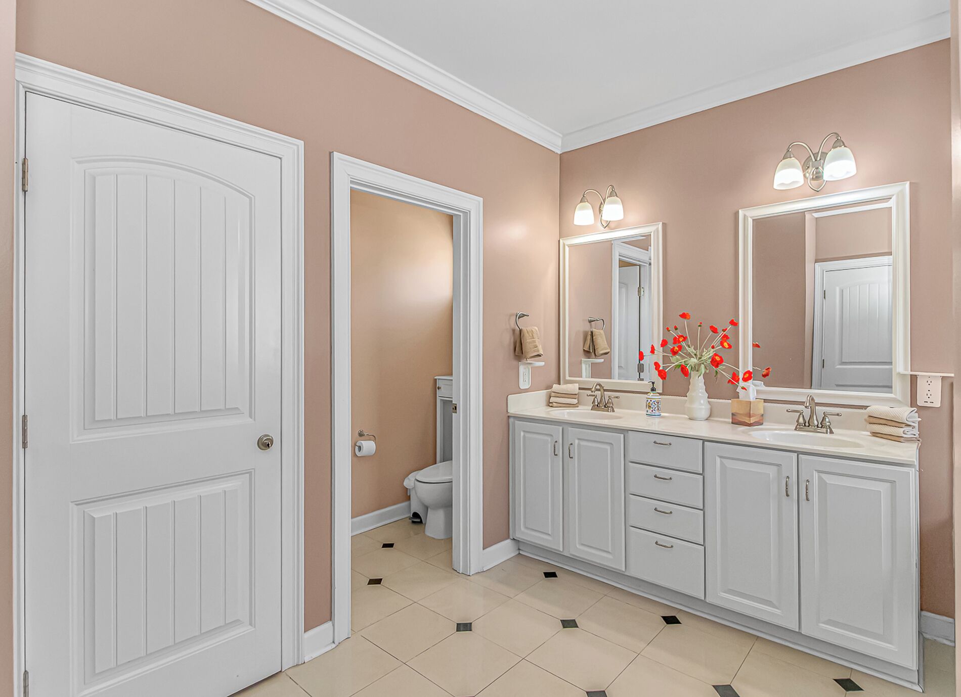 A bathroom with a white vanity, a large mirror, and a toilet.