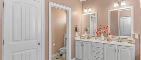 A bathroom with a white vanity, a large mirror, and a toilet.