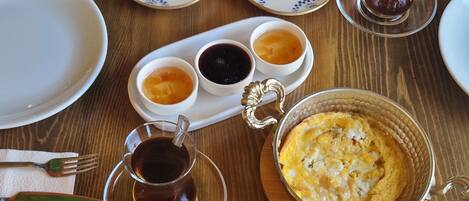 A wooden table with various breakfast items including fruits, pastries, and beverages.