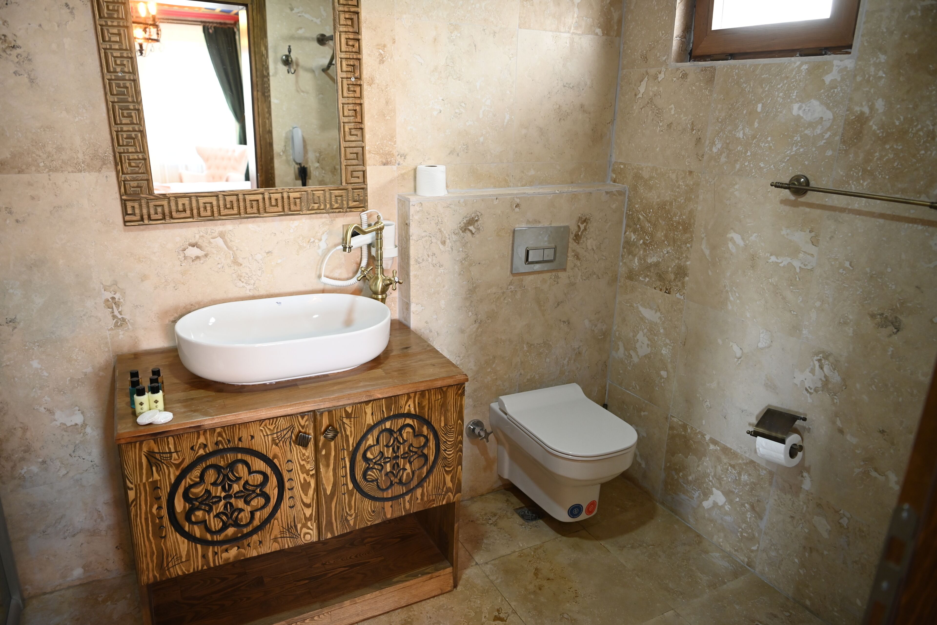 Un baño con tocador de madera, lavamanos blanco, inodoro y zona de ducha.