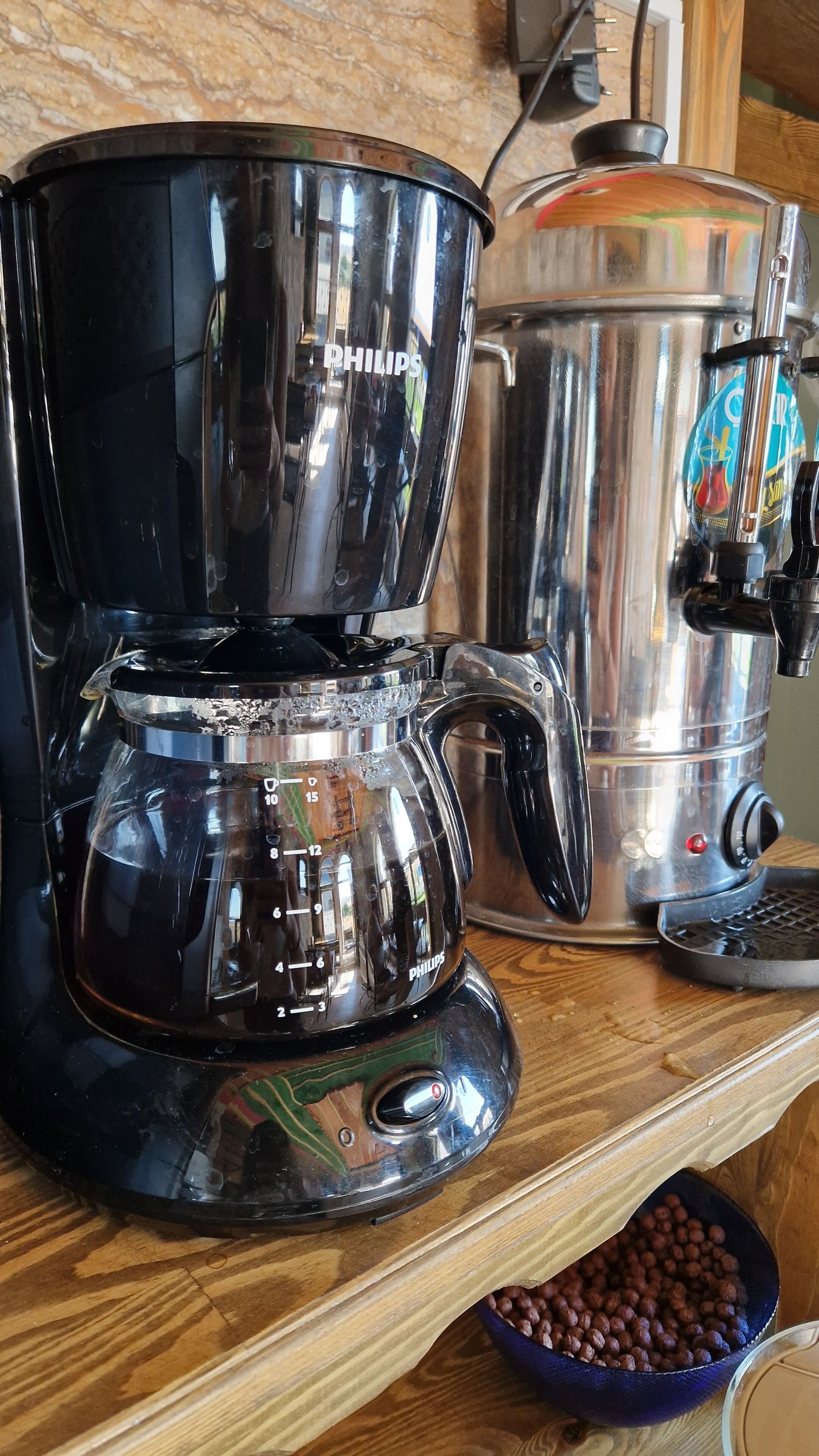 Eine Kaffeemaschine und ein Wasserspender auf einem Holzregal.